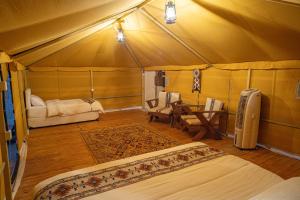 a room with a tent with a bed and a table at Desert Vibes Camp in Badīyah