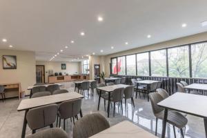 a dining room with tables and chairs and windows at GreenTree Inn Express Zhangjiagang Hexing Town Shazhou Professional Institue of Technology in Qiwei