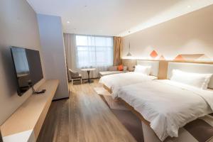 een hotelkamer met twee bedden en een flatscreen-tv bij Borrman Hotel Yongzhou High Speed Railway Station in Guzhuting