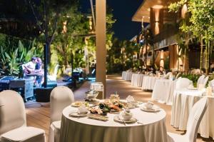 een rij tafels en stoelen met eten erop bij Riverton Hotel in Samut Songkhram