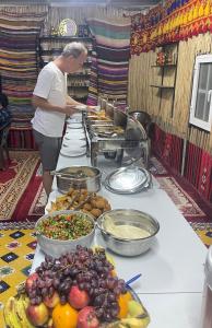 una donna in piedi di fronte a un buffet di cibo di Mirage Desert Camp a Al Raka