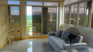 a living room with a couch and large windows at J Jireh Residences in San Jose del Monte