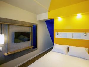 een slaapkamer met een bed met een gele muur bij ibis budget Recife Jaboatão in Recife