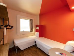 twee bedden in een kamer met oranje muren bij ibis budget Recife Jaboatão in Recife