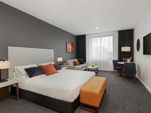 a bedroom with a large bed and a living room at Mantra Traralgon in Traralgon