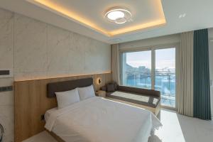 a bedroom with a bed and a large window at New CZ Nampo Hotel in Busan