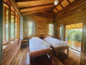 two beds in a room with wooden walls and windows at Cocoa Home in Ban Ko Phrao