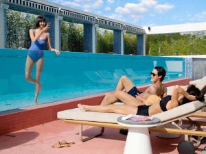 Tres personas en traje de baño sentadas en una piscina en Mondrian Seoul Itaewon, en Seúl