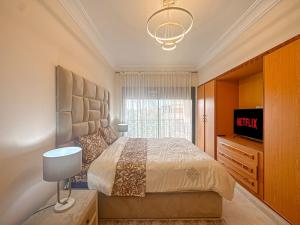 une chambre avec un grand lit et une télévision dans l'établissement Palmeraie chic à 10 mn du stade Piscine et confort, à Dar Caïd Layadi 16 autres photos
