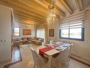une salle à manger avec une table et des chaises et un salon dans l'établissement Palmeraie chic à 10 mn du stade Piscine et confort, à Dar Caïd Layadi