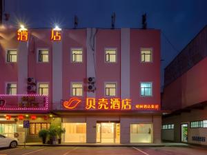 a pink building with neon signs in front of it at Shell Hotel Shnaghai Beiqiao Metro Station in Shanghai