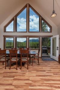uma sala de jantar com mesa e cadeiras e janelas grandes em Family-Friendly Cabin Rental with Mountain Vistas near West Glacier, Montana em West Glacier