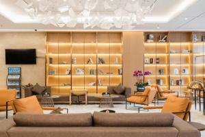 a lobby with couches and chairs and a television at Echarm Plus Hotel Nanning Convention and Exhibition Center Medical University in Nanning