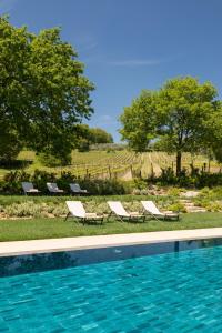 a swimming pool with two lounge chairs and trees at Godiluva in Palazzone