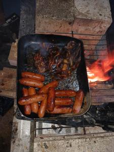 a pan filled with carrots and meat next to a fire at SeaSide Homestay in Korotogo