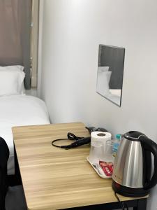 Una mesa de madera con una tetera encima, al lado de una cama. en GO INN Siriraj Wang Lang - โก อินน์ ศิริราช ตลาดวังหลัง Pro, en Bangkok Noi