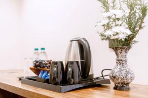 a tray with a coffee maker and a vase with flowers at Seaking Suites in Ernakulam