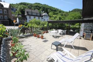 a patio with white chairs and tables and trees at Hotel Klasen in Cochem