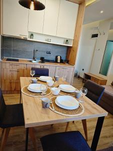 a wooden table with plates and wine glasses on it at Harmony, Residence Hill A85 in Kopaonik