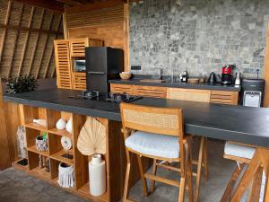 a kitchen with a large black counter and chairs at The Sawah Lodge, Seseh-Bali in Seseh