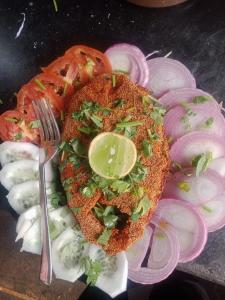 ein Teller mit Essen mit einem Sandwich mit einer Gabel und Zwiebeln in der Unterkunft Gokarna beach point rooms in Gokarn