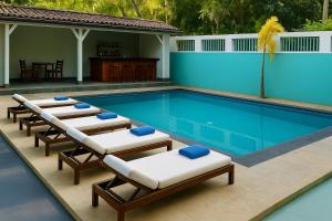 ein Schwimmbecken mit Liegestühlen und Stühlen darin in der Unterkunft Eros Green House in Unawatuna + 5 Fotos