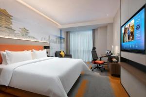 a hotel room with a bed and a flat screen tv at Hilton Garden Inn Nanchang Chaoyang Center in Nanchang