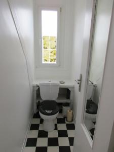 a bathroom with a toilet with a window and a checkered floor at Gwenhadu in Paimpol