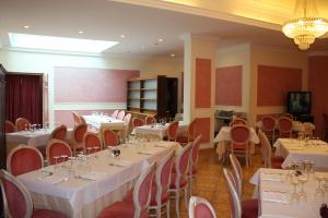 jadalnia z białymi stołami i krzesłami w obiekcie Grand Hotel degli Angeli w mieście San Giovanni Rotondo