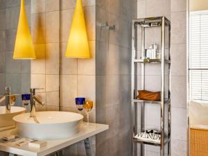 a bathroom with a sink and a mirror and lights at Too Hotel & Spa Paris - MGallery Collection in Paris