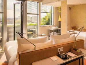 Una sala de estar con muebles blancos y una gran ventana. en Too Hotel & Spa Paris - MGallery Collection, en París