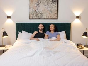 a man and woman sitting on a bed at The Sebel Canberra Campbell in Canberra +42 photos