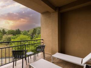 a balcony with two chairs and a view at Movenpick Resort and Spa Fruske Terme in Vrdnik