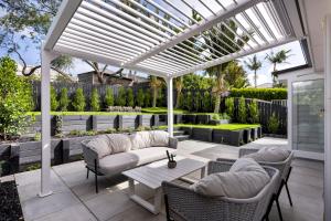a patio with a white pergola with chairs and a table at Luxury Ponsonby Villa in Auckland