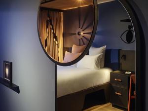 a room with a bed and a clock in a mirror at Tribe Paris Saint Ouen in Saint-Ouen