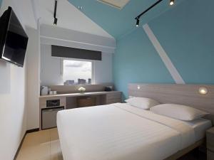 a bedroom with a large white bed and a window at ibis budget Phnom Penh Riverside in Phnom Penh