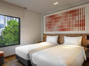 two beds in a room with a window at ibis Chiang Mai Nimman Journeyhub in Chiang Mai