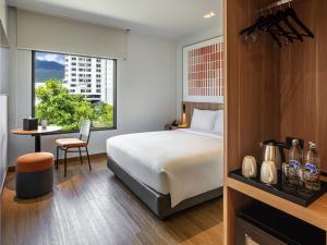 a bedroom with a bed and a desk and a window at ibis Chiang Mai Nimman Journeyhub in Chiang Mai