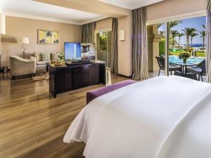 a hotel room with a bed and a living room at Rixos Sharm El Sheikh - Adults Only 18 Plus in Sharm El Sheikh