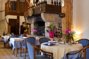 a restaurant with tables and chairs with wine bottles at Auberge Du Moulin Marin in Lapalisse