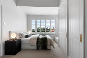 a white bedroom with a bed and a window at Luxury Ponsonby Villa in Auckland