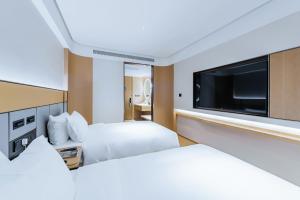 una habitación de hotel con dos camas y un televisor de pantalla plana en JI Hotel Shanghai Tonghe New Village Subway Station, en Baoshan