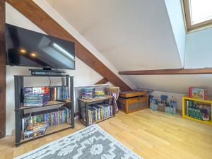 a living room with a flat screen tv and books at Grand Triplex 140m2 dans les Vosges in La Celle-sous-Gouzon