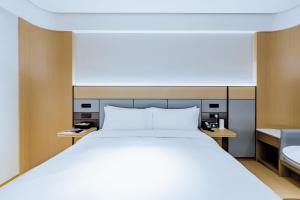 Un dormitorio con una gran cama blanca en una habitación. en JI Hotel Shanghai Tonghe New Village Subway Station, en Baoshan 12 fotos más