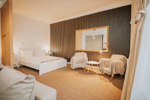 a bedroom with a bed and chairs and a mirror at Kossuth Apartments in Gheorgheni