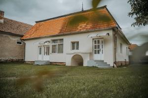 a white house with an orange roof on a yard at Kossuth Apartments in Gheorgheni