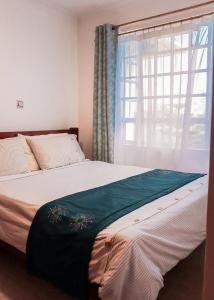 Stylish 3-BR Apt in Chuna, Kitengela في Athi River: غرفة نوم بسرير كبير مع نافذة