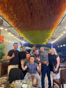 a group of people posing for a picture in front of a table at Cat & laundry hotel in Hanoi