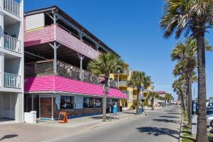 a pink building on the side of a street with palm trees at Sandpiper 304 in Tybee Island