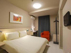een hotelkamer met een wit bed en een rode stoel bij Jinjiang Inn Yueyang Railway Station in Yueyang